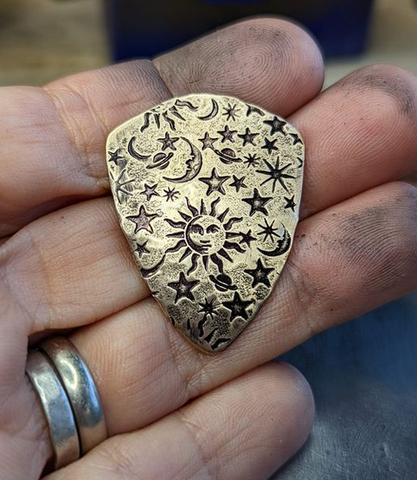 bronze shield guitar pick with sun moon and stars