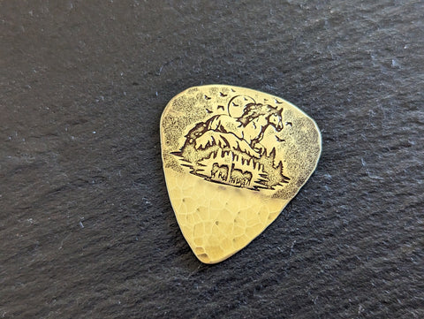 Brass guitar pick with horses , mountains and a hammered texture - playable
