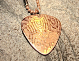Copper guitar pick necklace with swirling waves of sound