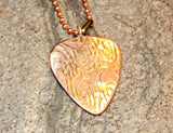 Copper guitar pick necklace with swirling waves of sound