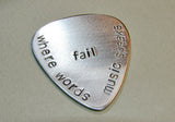 Stamped aluminum guitar pick where words fail music speaks