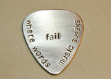 Stamped aluminum guitar pick where words fail music speaks